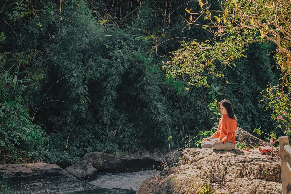 Woman sitting on a stone near a stream