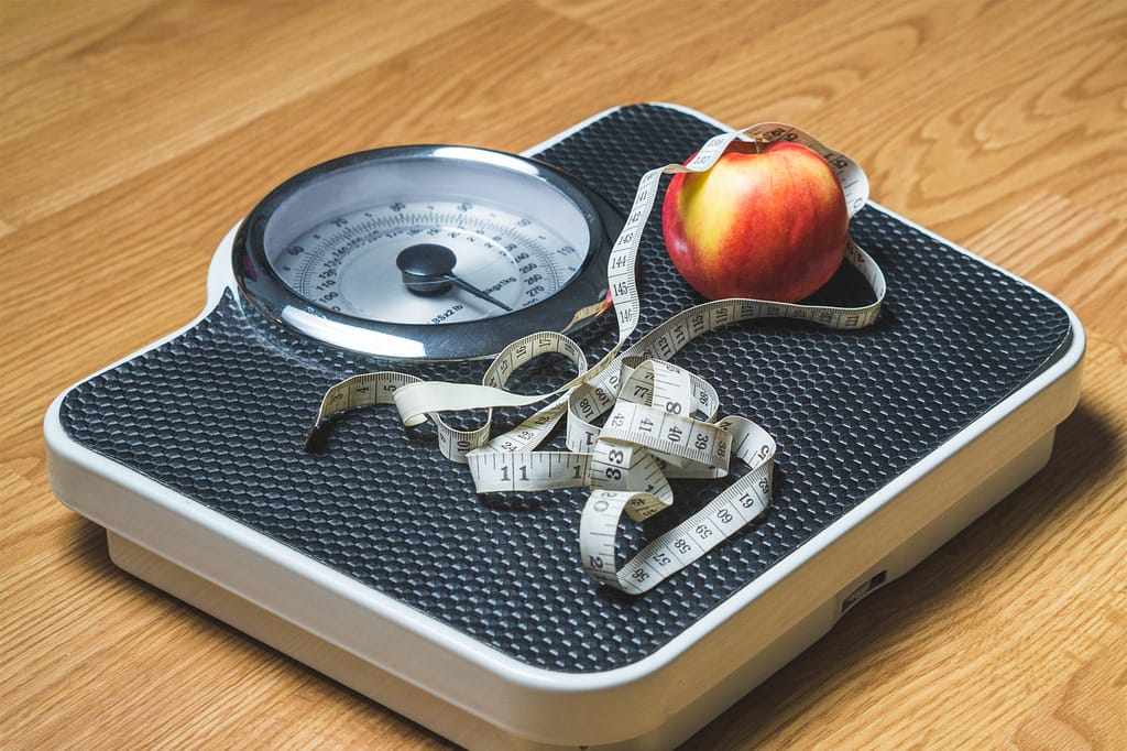 A scale with a measuring tape and apple on top