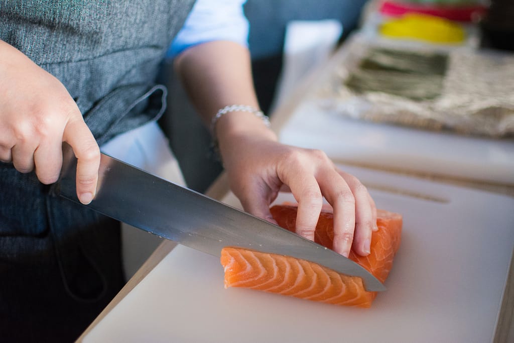 Person slicing salmon on a cutting board
