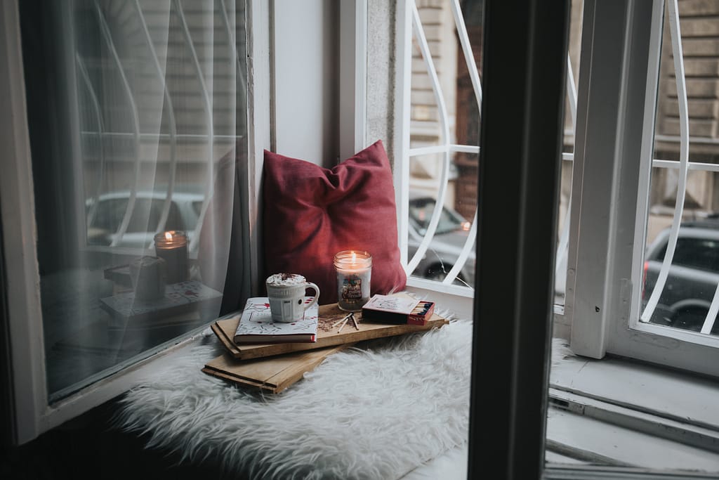 Windowsill with a pillow, candle and a journal