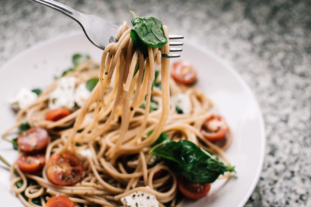 A bowl of pasta with tomatoes and basil