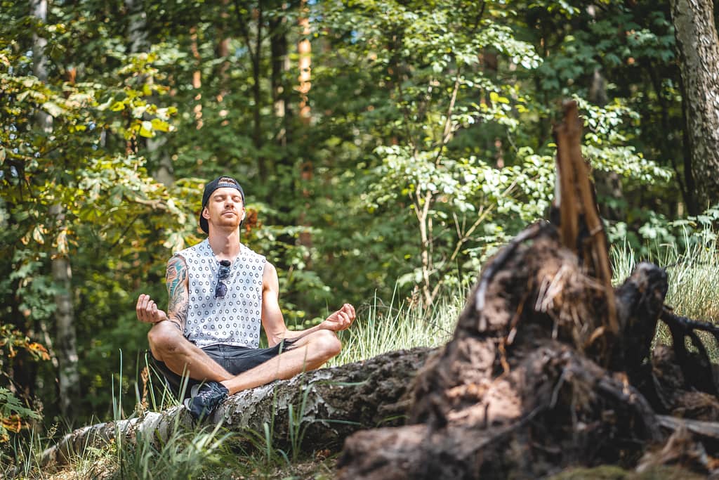 A man meditating on a tree log