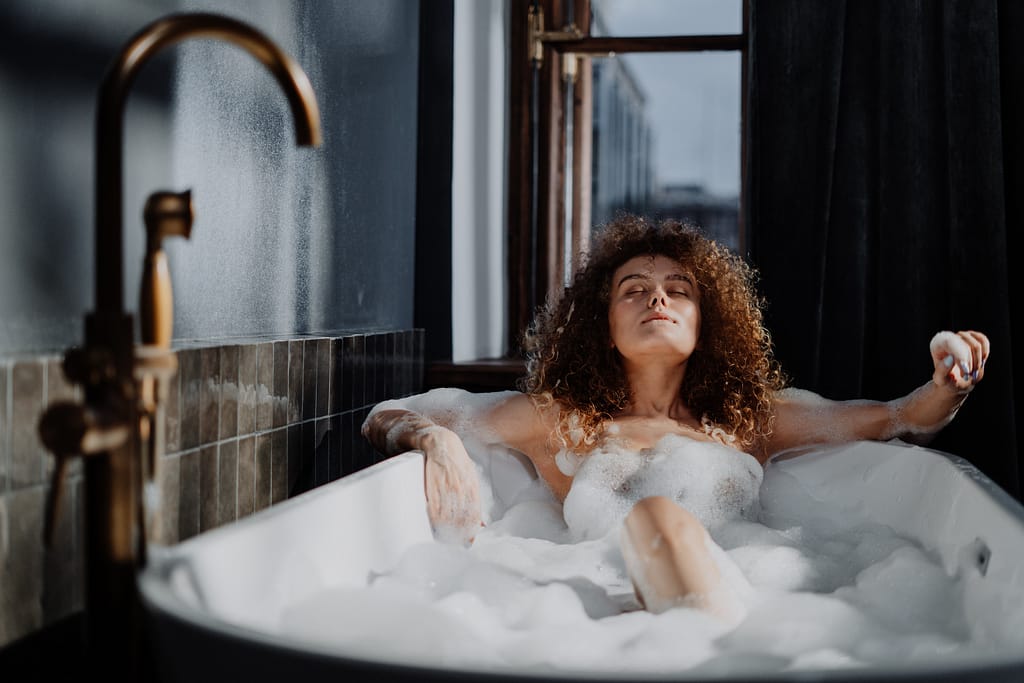 A woman taking a bubble bath to practice self-care