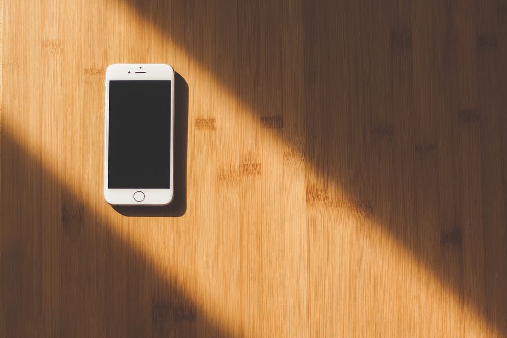 An Iphone lying on a hardwood floor