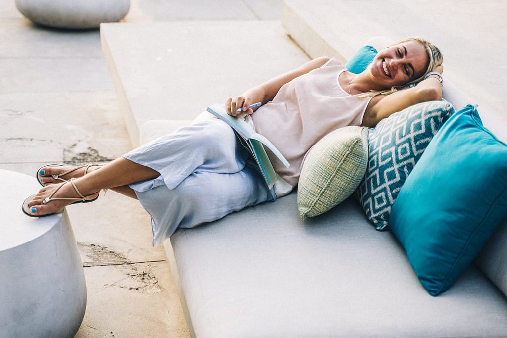 A woman journaling and smiling on her couch