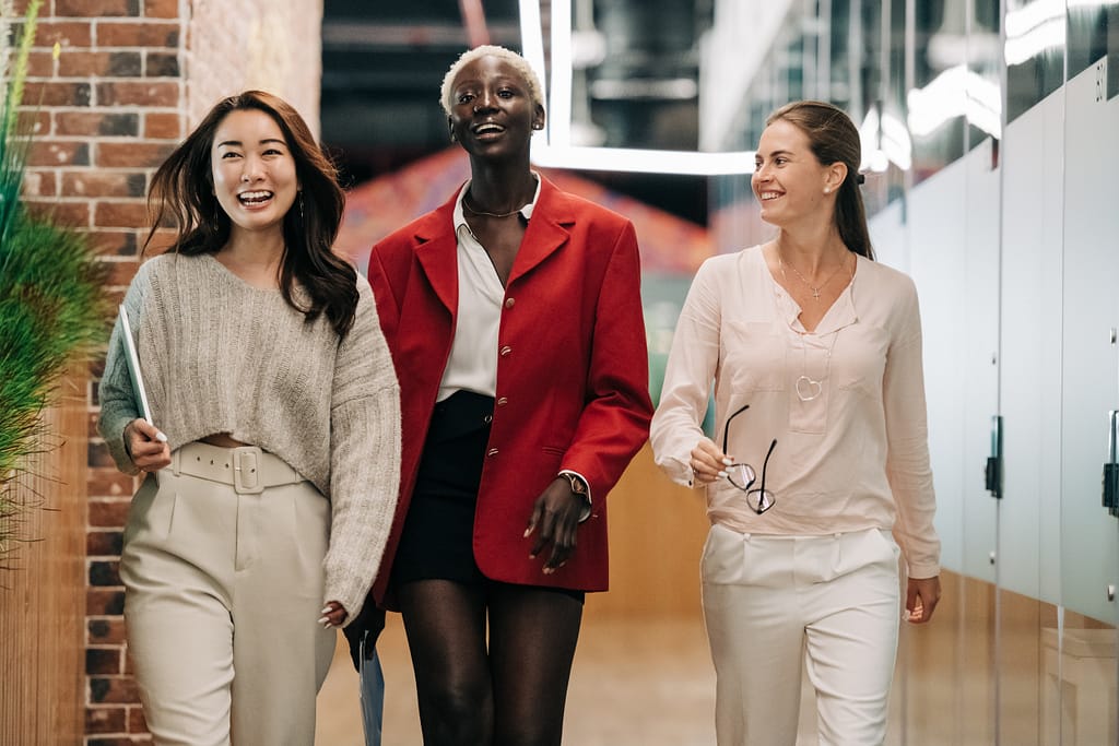 A group of diverse women walking in an office and smiling
