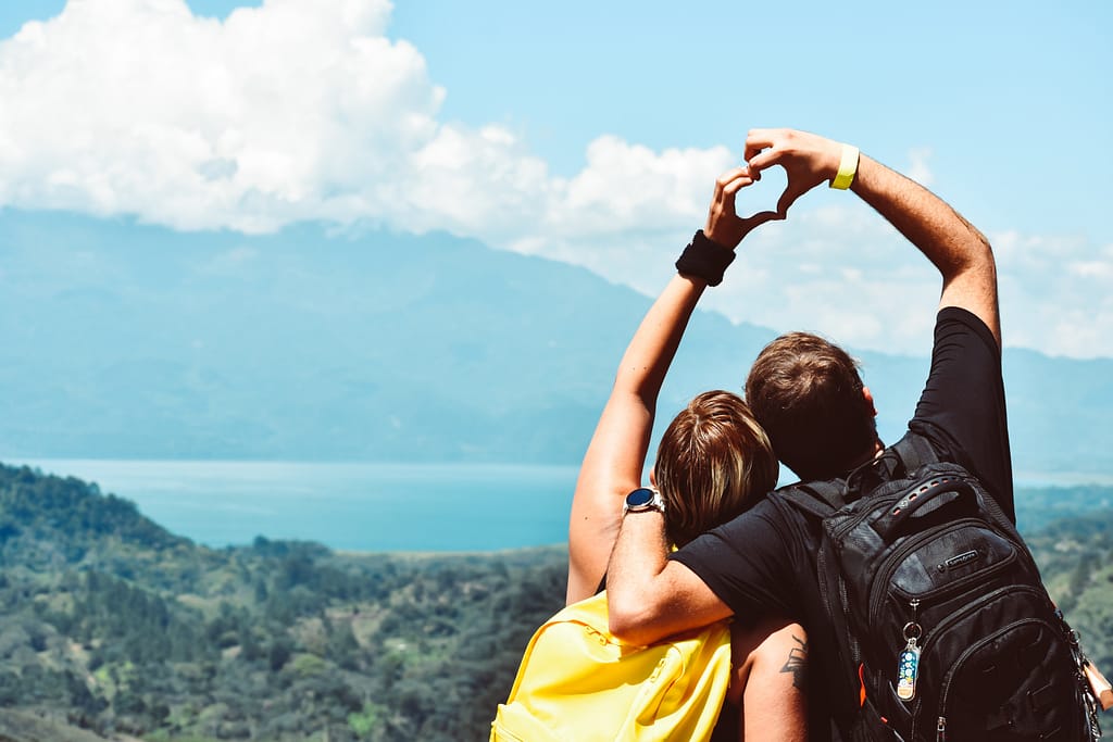 A couple facing a mountain and their hands in the shape of a heart