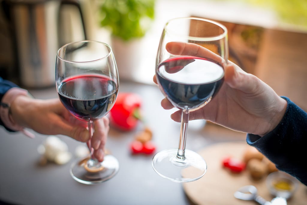 Close up of two people holding two glasses of red wine