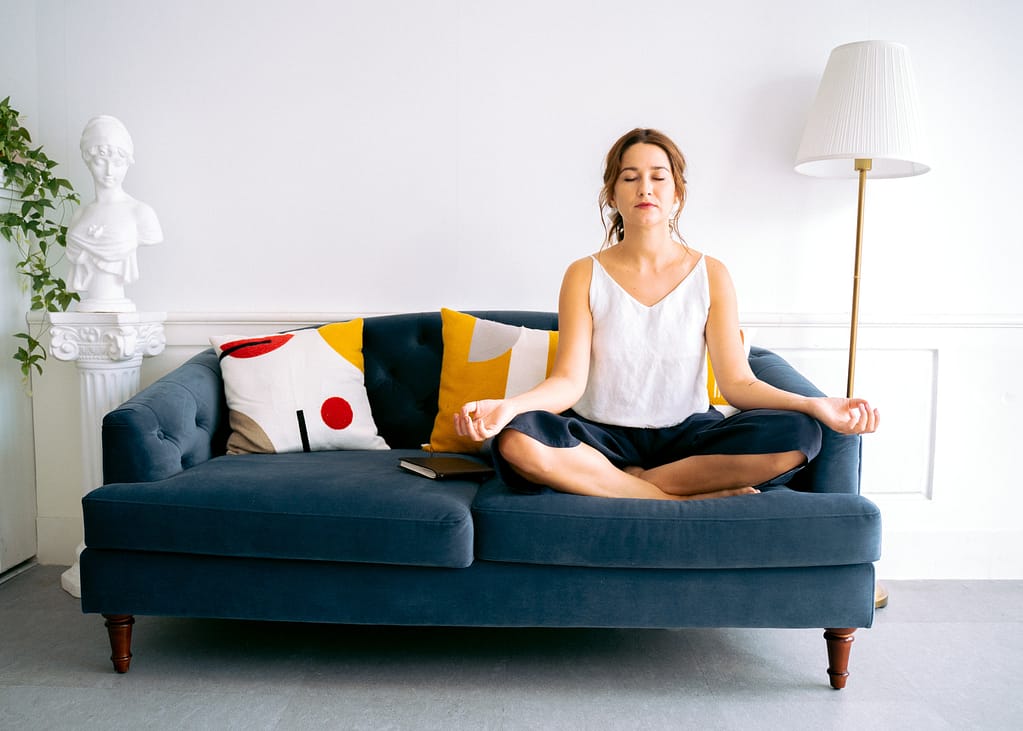 How to do meditation at work: a woman sitting cross legged on the couch