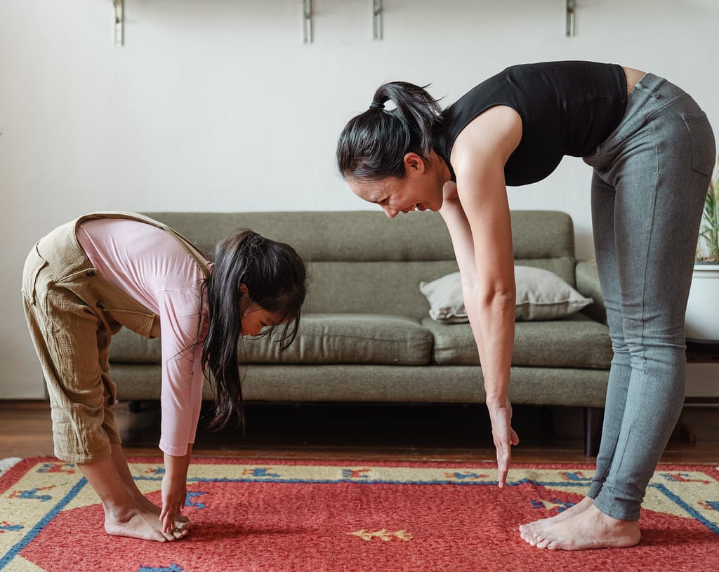 A mother and daughter stretching together at home