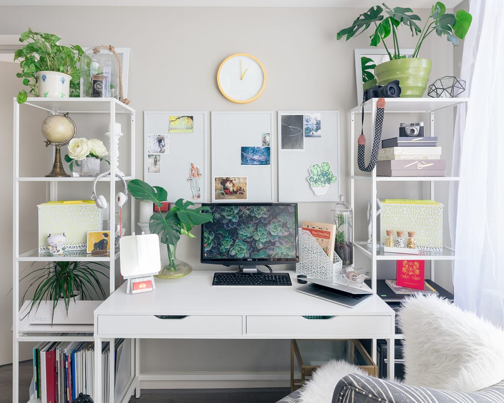 A desk with a desktop computer and lots of plants
