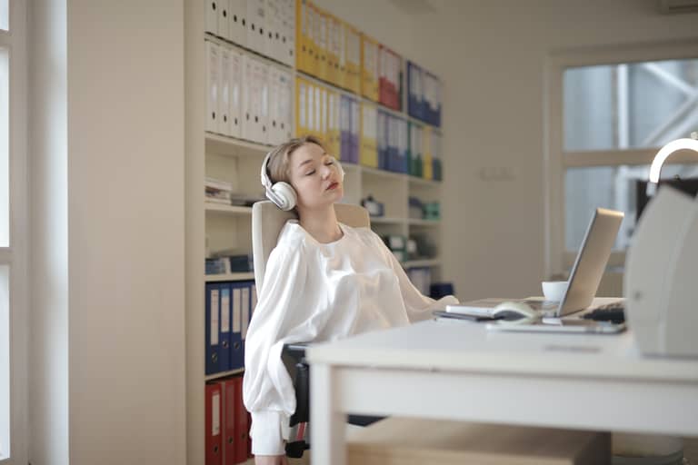 A woman asleep at her desk with headphones on