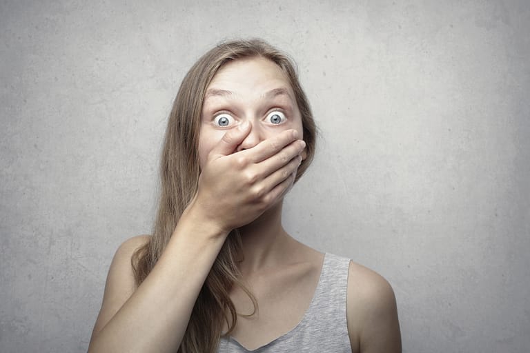 How to improve your mental health with a woman looking surprised covering her mouth