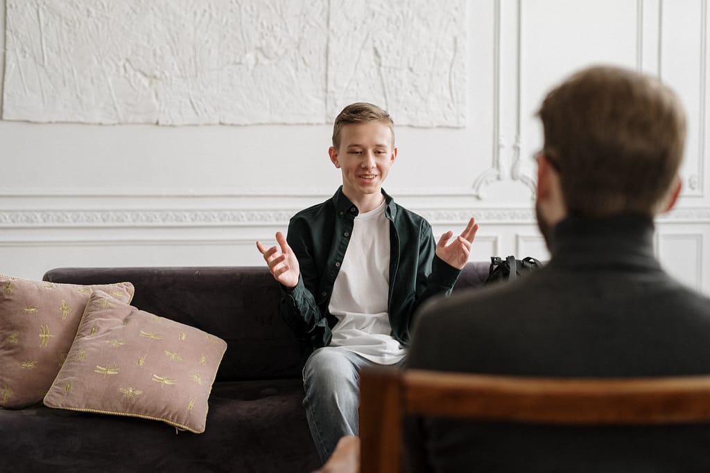 A teenage boy smiling while talking to his therapist