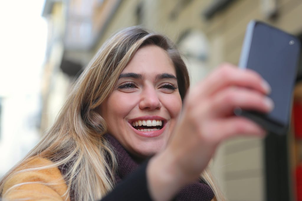 A woman smiling while looking at the best meditation apps on her phone