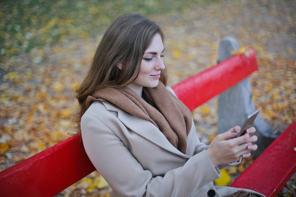 A woman sitting on a bench looking at her phone