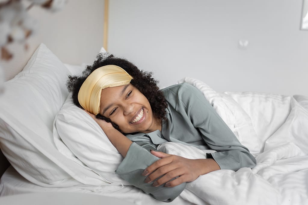 How to wake up feeling refreshed with a woman lying on her side smiling because she know how to wake up feeling refreshed in the morning
