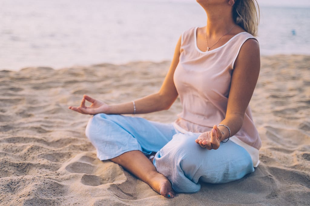 A woman meditating on beach beach
