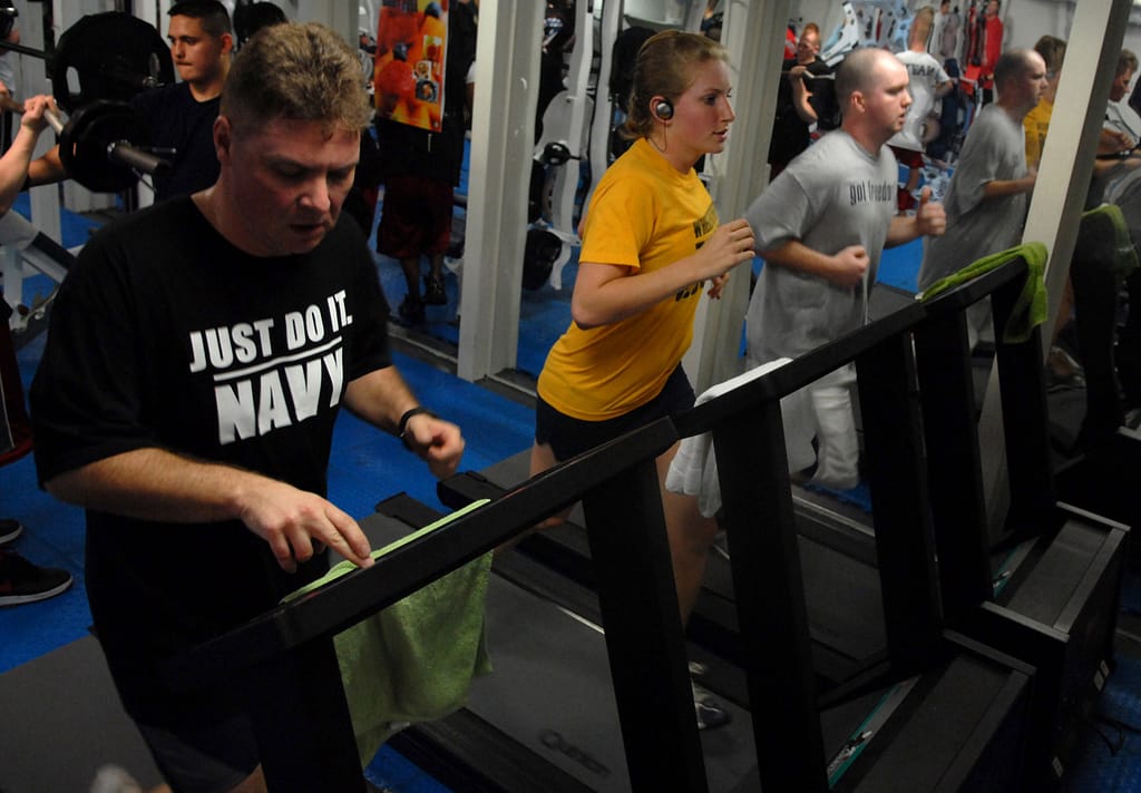 Three people walking on treadmills in a gym