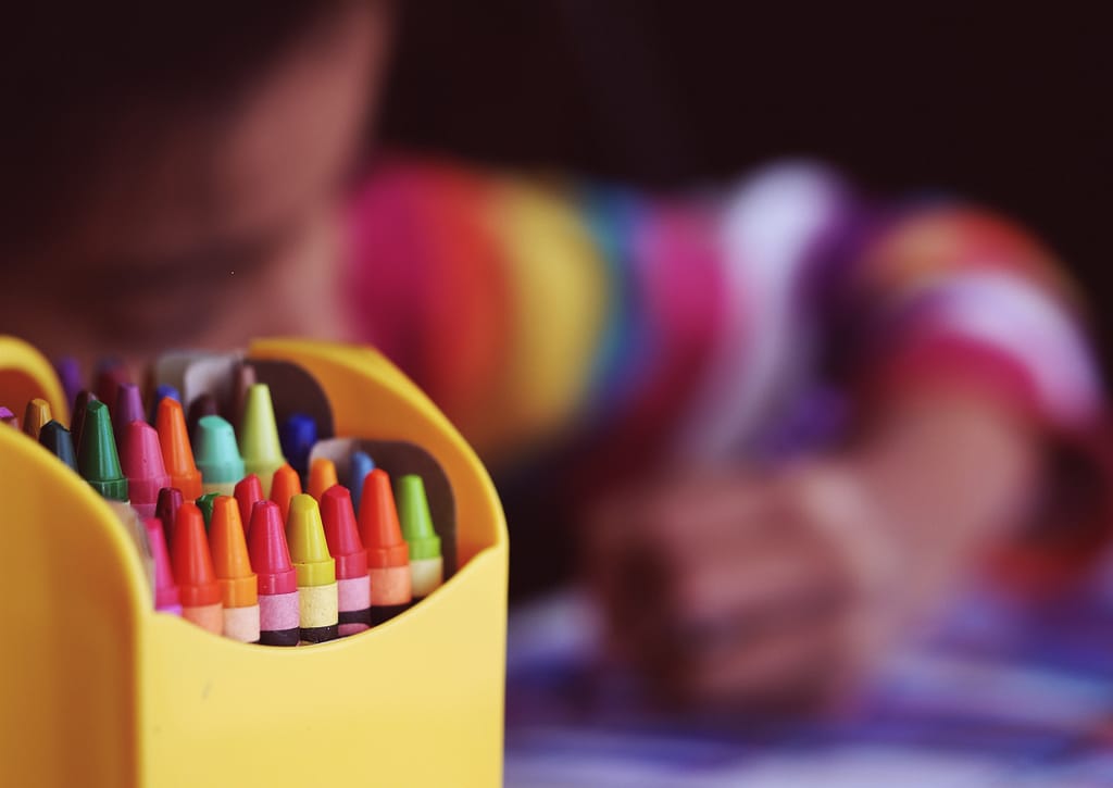 A box of crayons next to a child drawing during the coronavirus lockdown