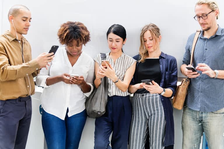 A group of women looking at their phones while standing